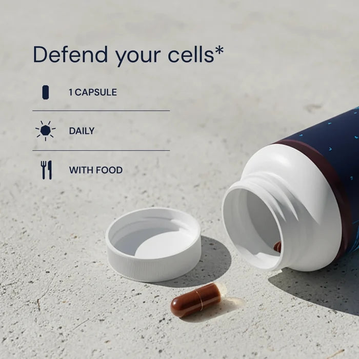 Open supplement bottle with a capsule on a concrete surface, text 'Defend your cells' displayed.