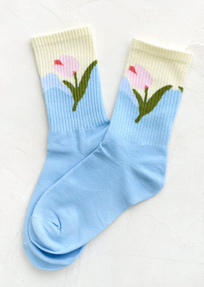 A pair of socks in sky blue with pink tulip design at ankle.