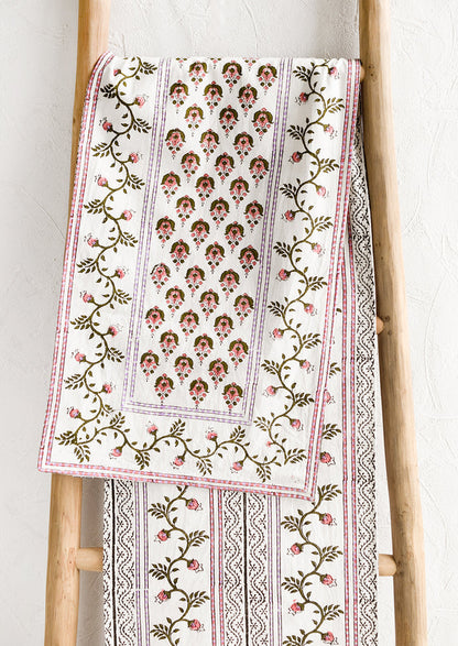 A block printed white table runner with pink, green and lavender floral print.