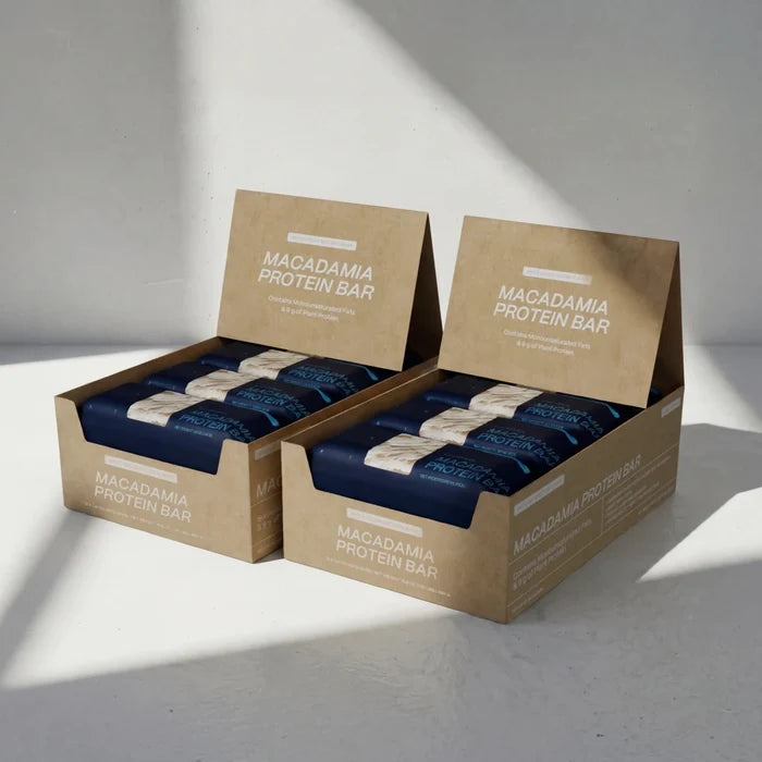 Two boxes of White Cocoa Butter Macadamia Protein Bars on a light gray background