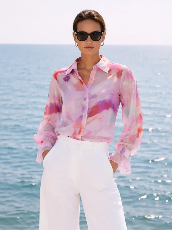 Woman wearing a colorful blouse and sunglasses by the ocean