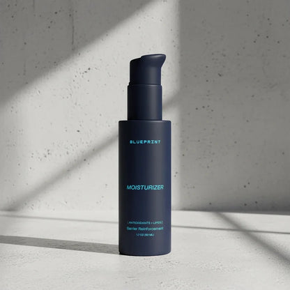 Blue bottle of Blueprint moisturizer on a gray concrete background