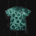 A green and black tie-dye t-shirt from Reflections, featuring a small white rectangular Crystal Eyes logo on the upper left chest, displayed on a dark, textured background.