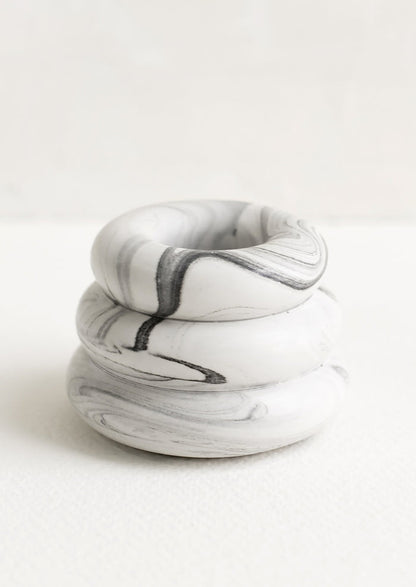 A taper candle holder with 3-layer stacked donut shape in grey and white marble.